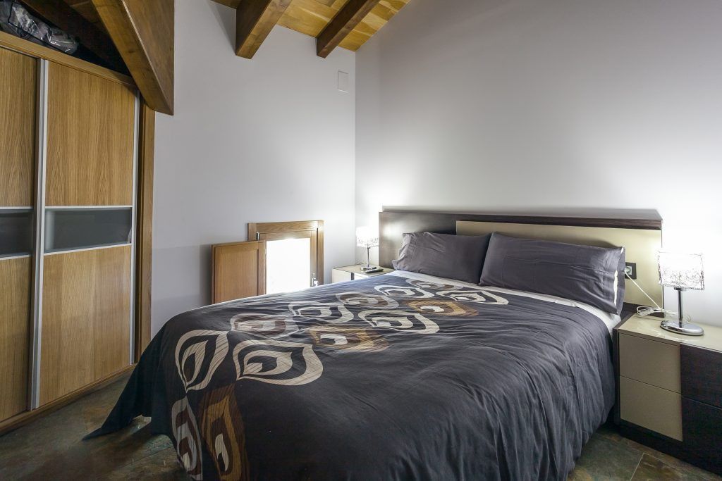 A bedroom with a bed, nightstands, a lamp, and a wardrobe.