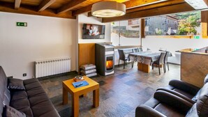 A modern living room with a sofa, a table, a fireplace, and a TV. - El Abrigaño del Cañon I y II (Valle de Sedano)