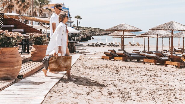 A beachside walkway with wooden loungers and thatched umbrellas, leading to a sandy beach. - Hotel Almira (Pineios)