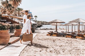 A beachside walkway with wooden loungers and thatched umbrellas, leading to a sandy beach. - Hotel Almira (Pineios)