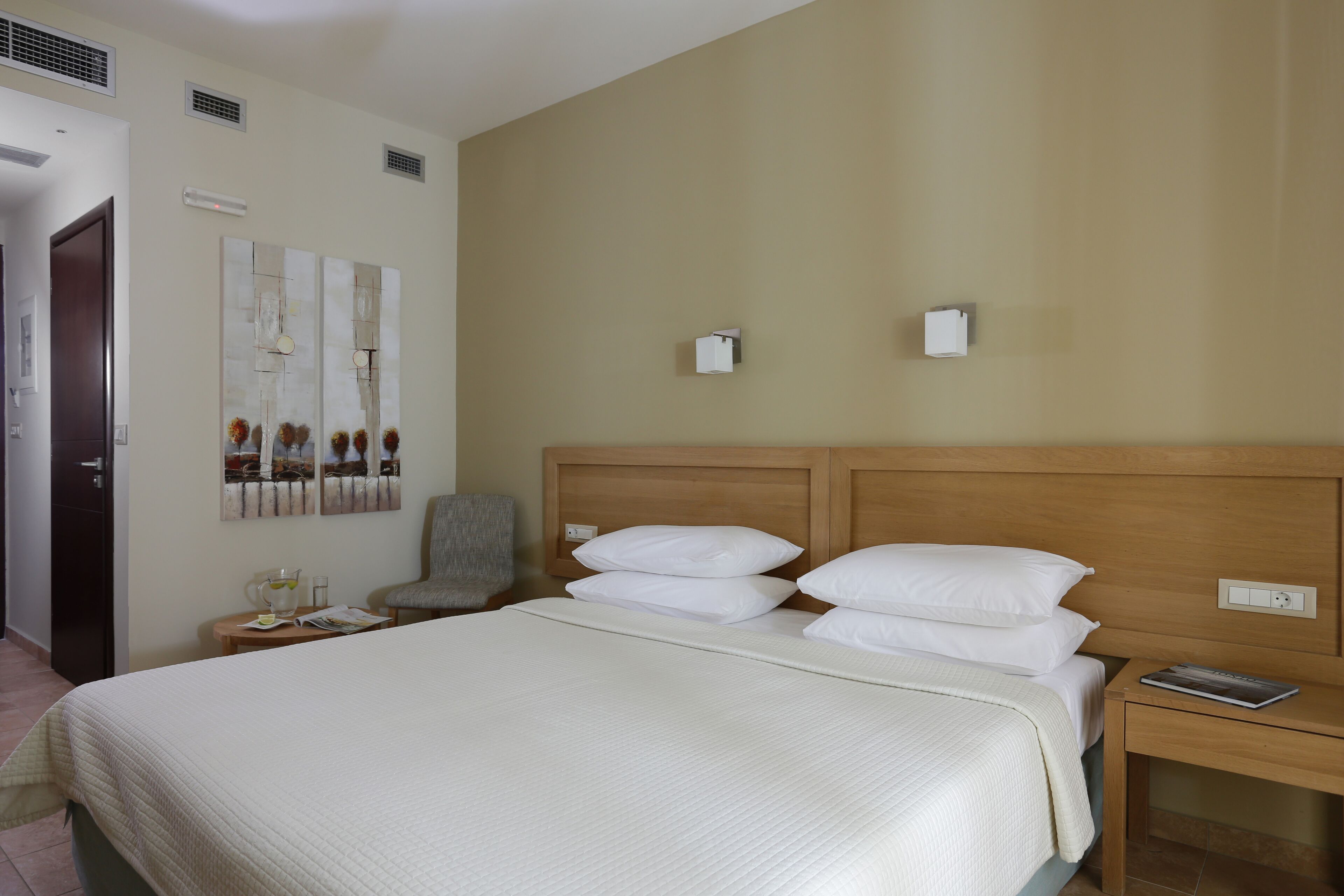 Ein Hotelzimmer mit einem großen Bett, einem hölzernen Kopfteil, einem Nachttisch mit einer Lampe und einem Sessel.