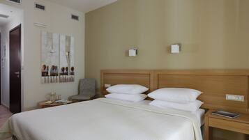 Ein Hotelzimmer mit einem großen Bett, einem hölzernen Kopfteil, einem Nachttisch mit einer Lampe und einem Sessel.