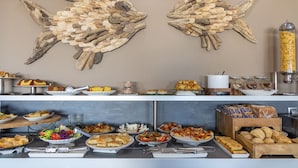A buffet setup with various food items and a decorative wall piece. - Hotel Almira (Pineios)