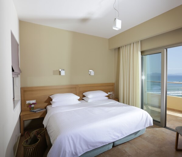 A hotel room with a large bed, a nightstand, a lamp, and a view of the ocean through a sliding glass door. - Hotel Almira (Pineios)