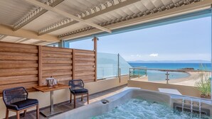 A balcony with a hot tub, seating, and a view of the beach. - Hotel Almira (Pineios)