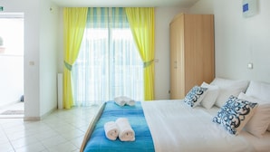 Quarto de hotel com cama, guarda-roupa e janela com cortinas.