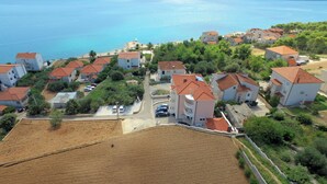 Vista aérea de uma área residencial costeira com casas, uma praia e um mar azul e límpido.