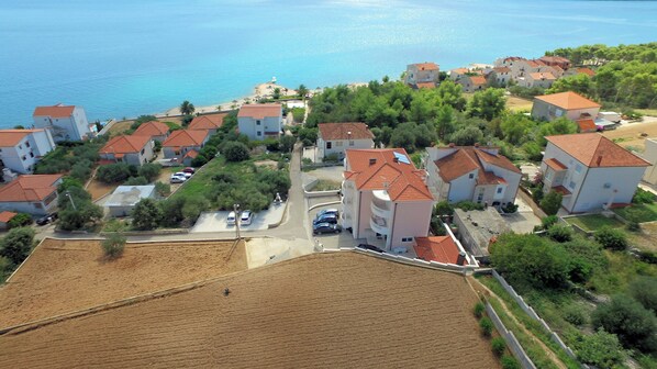 Vista aérea de una zona residencial costera con casas, una playa y un mar azul claro.