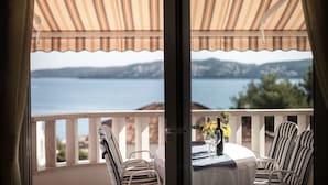 Uma varanda com vista para o mar, uma mesa com cadeiras e um vaso com flores.