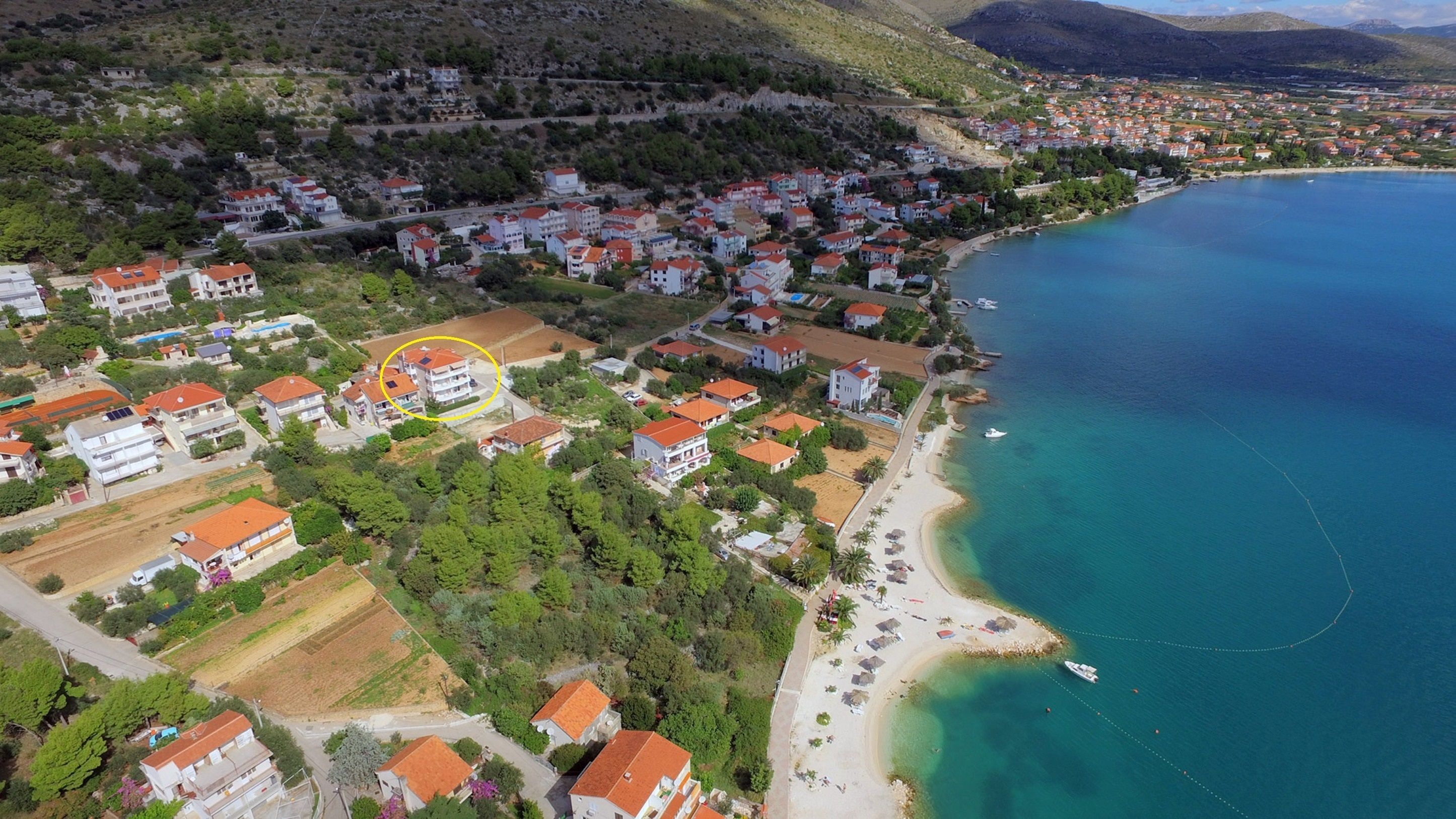 Ett flygbildsbild av en kuststad med bostadshus, en strand och ett klart, blått hav.