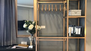 A modern hotel room with a black dresser, a mirror, a wardrobe with multiple shelves, and a wicker basket. - Stay in Style The Heart of Nimman R306A (Chiang Mai)