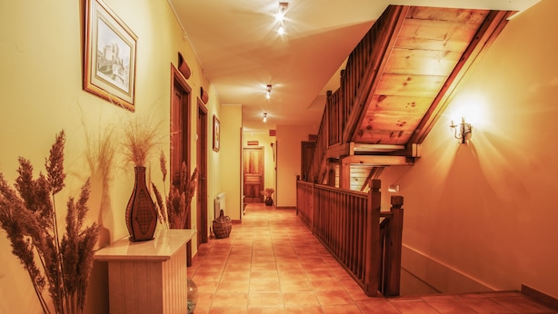 A hallway with a wooden staircase, tiled floor, and wall-mounted lights. - Hotel Rural Tirontillana (Cuellar)