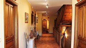 A hallway with wooden doors, a white console table with decorative items, and a tiled floor. - Hotel Rural Tirontillana (Cuellar)