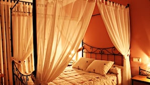 A bed with a canopy, a bedside table, and a wall-mounted light fixture. - Hotel Rural Tirontillana (Cuellar)