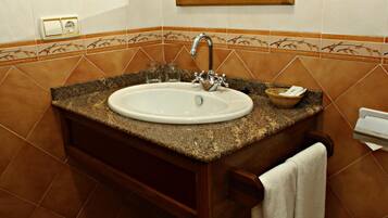 A bathroom with a granite countertop sink, a wooden vanity, and a towel rack.