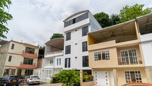 A multi-story residential building with a garage, a covered parking area, and a small garden. - Ayenda 1422 Caney (Cali)