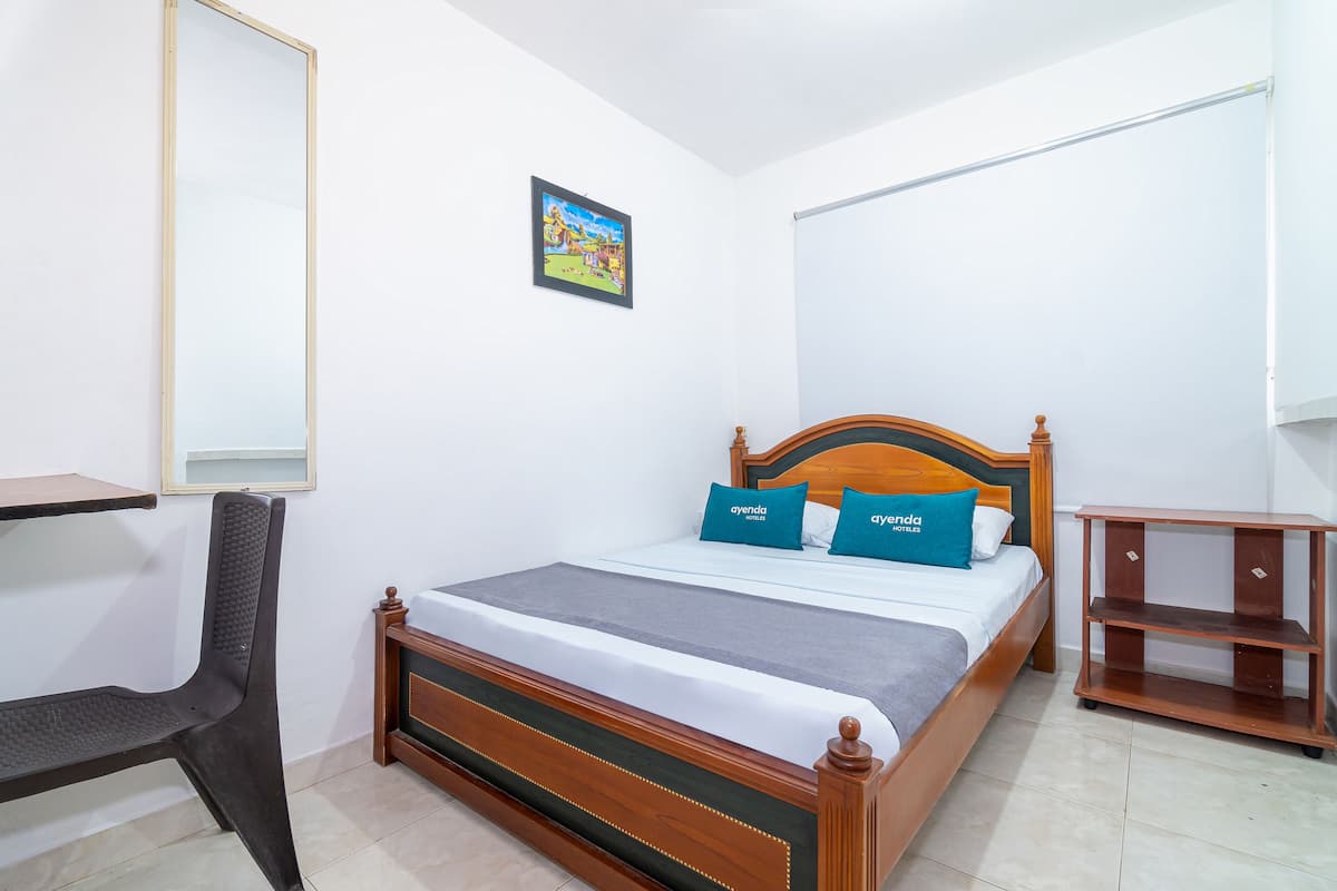 A neatly arranged bedroom with a bed, a chair, a small table, and a shelf.
