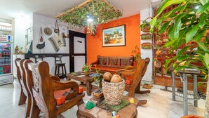 A cozy living room with a wooden sofa, a coffee table with decorative items, and a hanging plant. - Ayenda 1422 Caney (Cali)