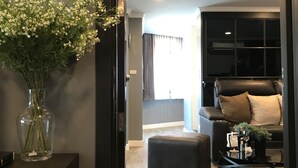 Un salon moderne avec un canapé noir, une table basse et un vase rempli de fleurs blanches.
