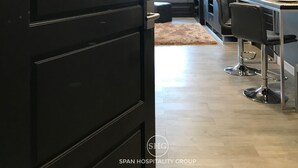 Une cuisine moderne avec un coin repas, une porte noire portant un numéro et une partie visible du salon.