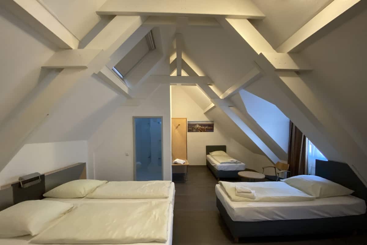 Ein Zimmer mit zwei Betten, einem kleinen Tisch und einer Tür zu einem anderen Raum.