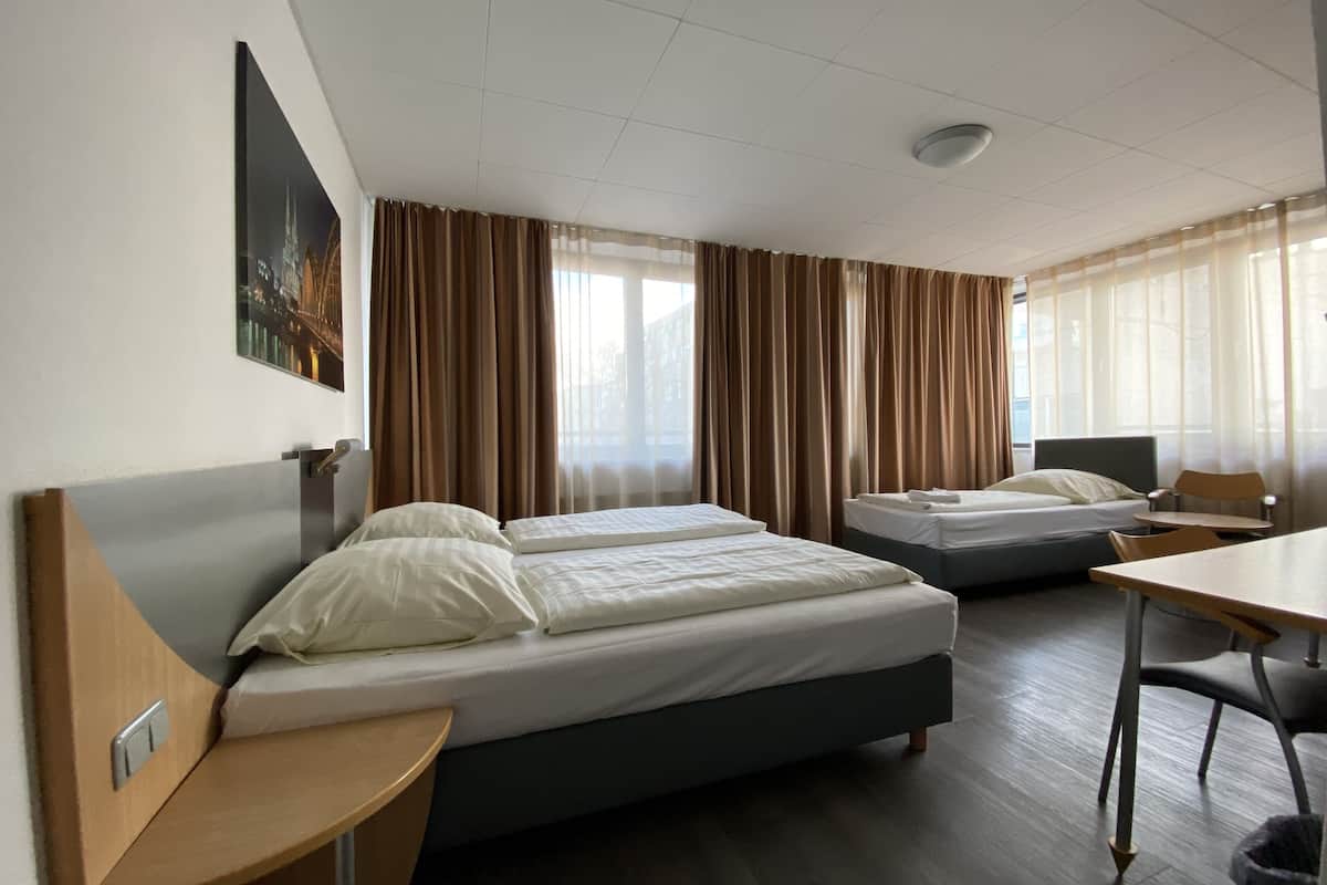 Ein Hotelzimmer mit zwei Betten, einem Schreibtisch und einem Stuhl.