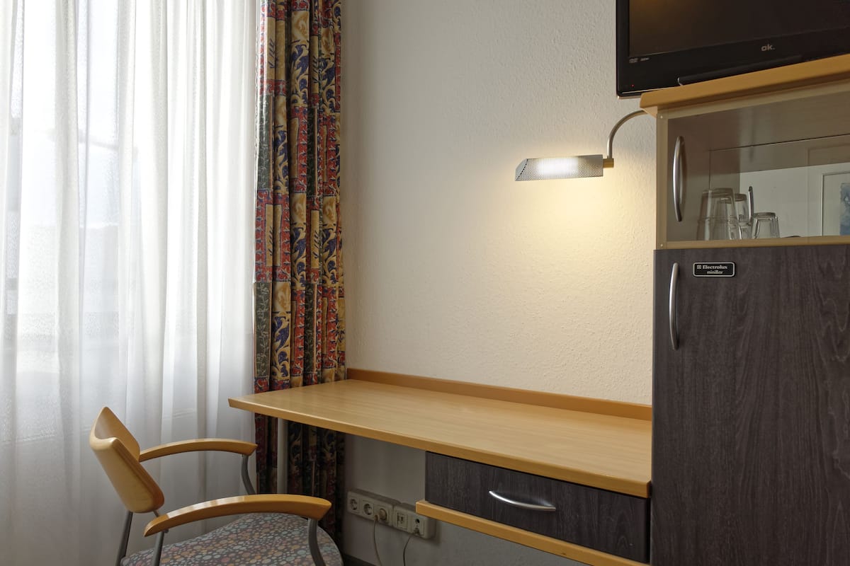Eine kleine Küchenzeile mit Holzausstattung, einem Stuhl und einem Kühlschrank.