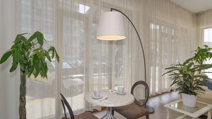 A room with a round table, two chairs, a floor lamp, and two potted plants. - Hotel Stella d'Italia (Viareggio)