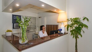 A reception desk with a computer, a lamp, and a potted plant. - Hotel Stella d'Italia (Viareggio)