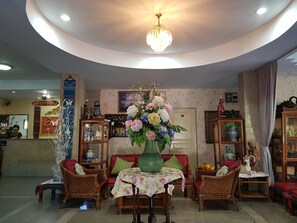 A reception area with a chandelier, floral centerpiece, wicker furniture, and a reception desk. - Wiang Inn Mansion (Chiang Mai)