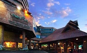 A modern building with a prominent sign, a covered outdoor area, and a clear sky. - Wiang Inn Mansion (Chiang Mai)