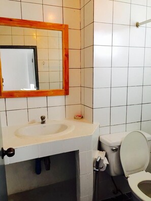 A bathroom with a white sink, a mirror with a wooden frame, a toilet, and a towel dispenser. - Wiang Inn Mansion (Chiang Mai)