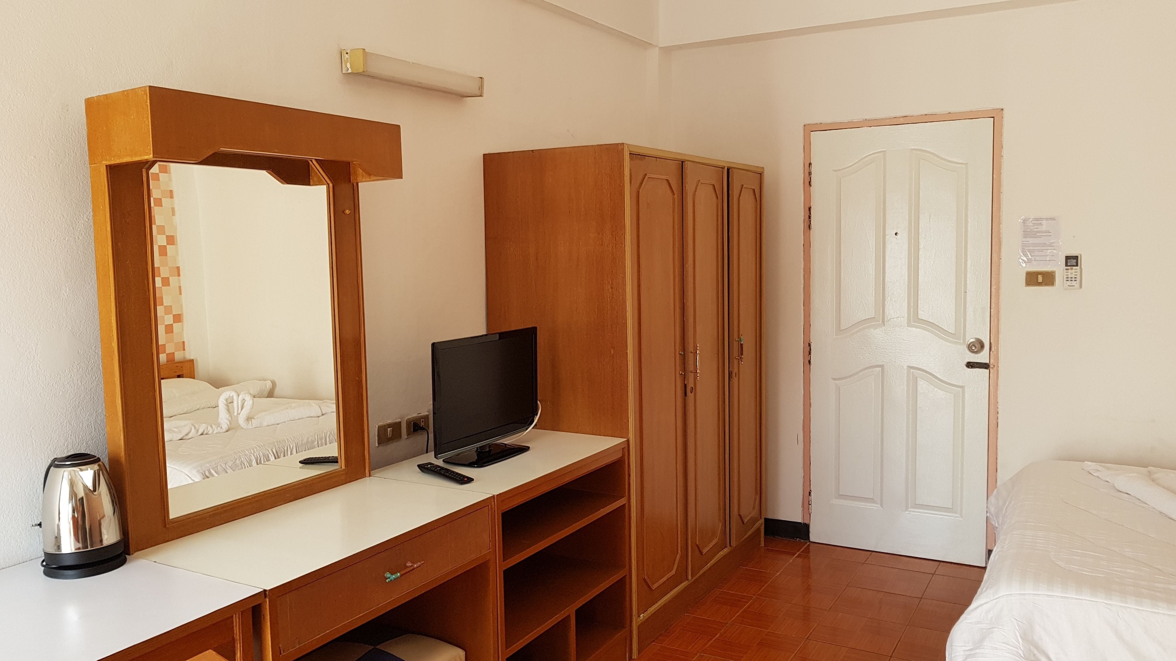 Quarto de hotel com uma mesa de madeira, televisão, guarda-roupa e cama.