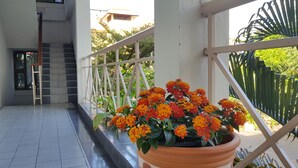 A balcony with a potted plant of orange and red flowers, a white railing, and a tiled floor. - Wiang Inn Mansion (Chiang Mai)