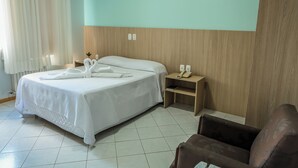 A hotel room with a bed, a bedside table with a phone, and a chair. - Center Hotel (Xanxere)