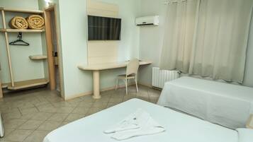 Una habitación de hotel con cama, escritorio, silla, armario y televisor.