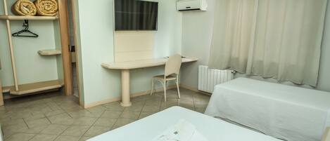 A hotel room with a bed, a desk, a chair, a wardrobe, and a TV.