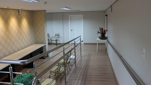 A hallway with a seating area, a staircase, and a door. - Center Hotel (Xanxere)
