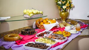 A buffet table with various food items and a vase of flowers. - Center Hotel (Xanxere)