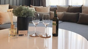 Un saló modern amb una taula rodona de marbre, dues copes de vi, una ampolla de vi, una planta en test i un senyalitzador que indica que està prohibit fumar.