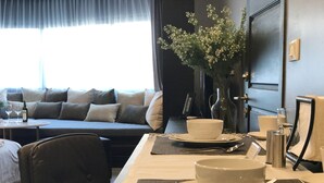 Habitació d'hotel amb zona de menjador, un sofà, un ram de flors i una porta.