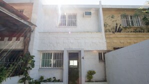 A two-story building with a white exterior, a small entrance, and barred windows. - Tohoku Townhouse 4 (Playa del Carmen)