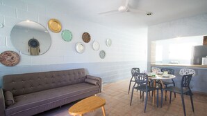 A modern living room with a grey sofa, wooden coffee table, and a dining area with a round table and chairs. - Tohoku Townhouse 4 (Playa del Carmen)