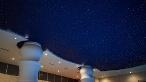 Techo con cielo estrellado en un interior moderno con paredes de mármol y columnas blancas.