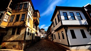 Una estrecha calle adoquinada bordeada por edificios históricos con arquitectura tradicional, incluyendo balcones y ventanas a la vista.
