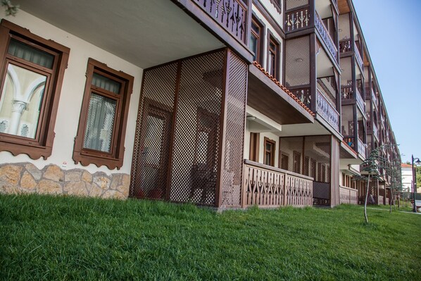 A multi-story building with balconies, a stone facade, and a grassy area in front. - Taraklı Termal Suite (Tarakli)