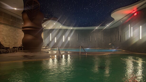 Una piscina con techo estrellado, una gran escultura y una iluminación moderna.