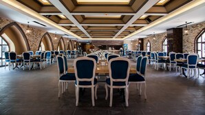 Un comedor amplio con mesas largas y sillas azules, que destaca por un diseño moderno del techo y paredes de ladrillo.