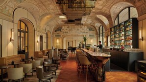 A bar area with a long counter, multiple seating options, and a piano.