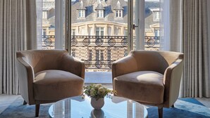 A room with two armchairs facing a large window with a view of a building. - Mandarin Oriental Lutetia, Paris (Paris)